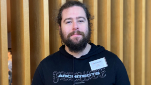 Image shows Connor's head and shoulders shot facing the camera wearing a navy blue hoodie