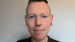 Image shows Ryan Smiling to camera and sporting some rather fabulous facial piercings