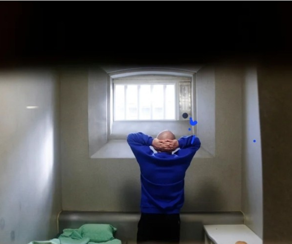 Image shows man in prison cell.